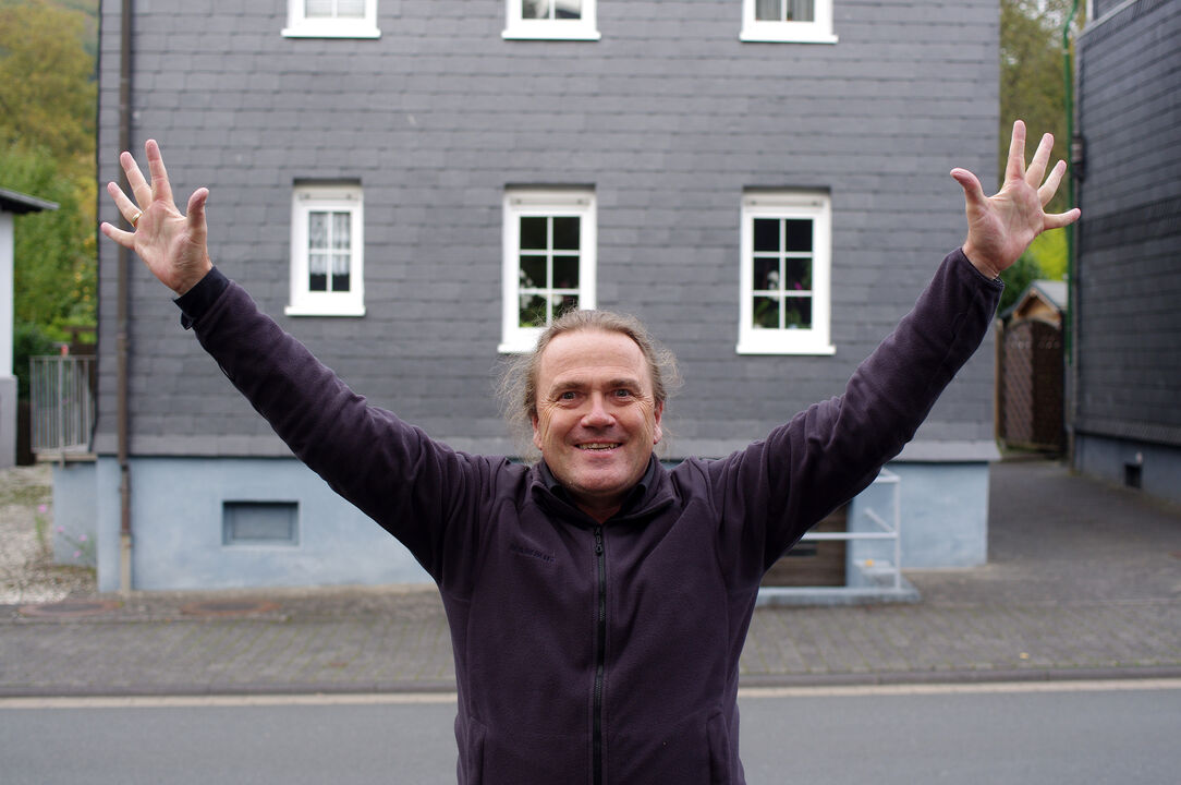 Thomas Kellner cheers in front of one of his half-timbered houses